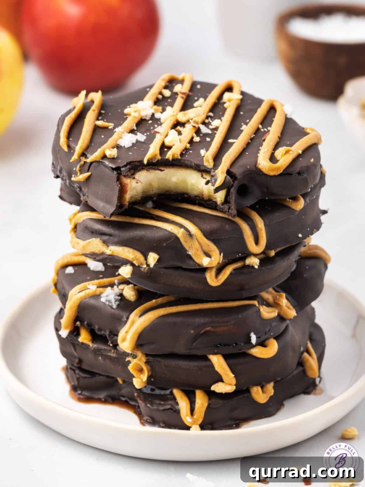 A stack of perfectly chocolate covered apple slices on a white plate