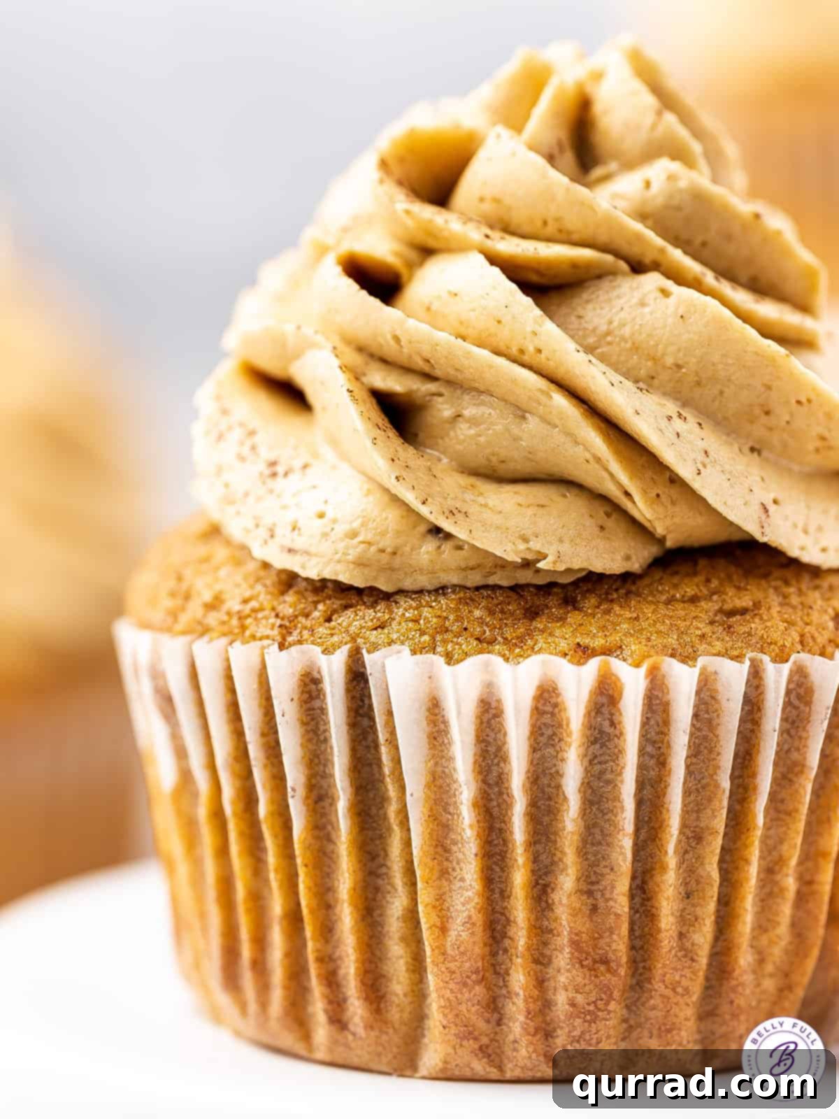 A close-up shot of a coffee cupcake, showing the soft crumb and a generous swirl of fluffy coffee buttercream frosting.