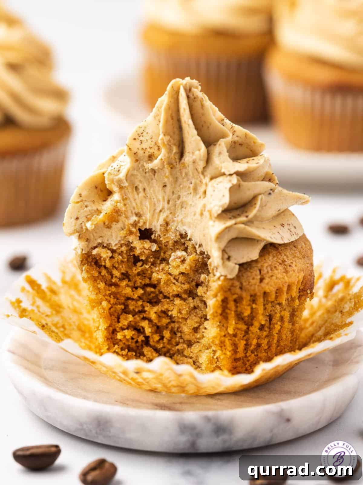 A coffee cupcake with a bite taken out, revealing the moist interior and rich buttercream.