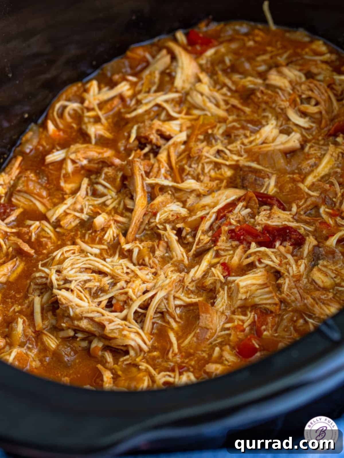 Shredded chicken simmering in the slow cooker, ready to be served in tacos.