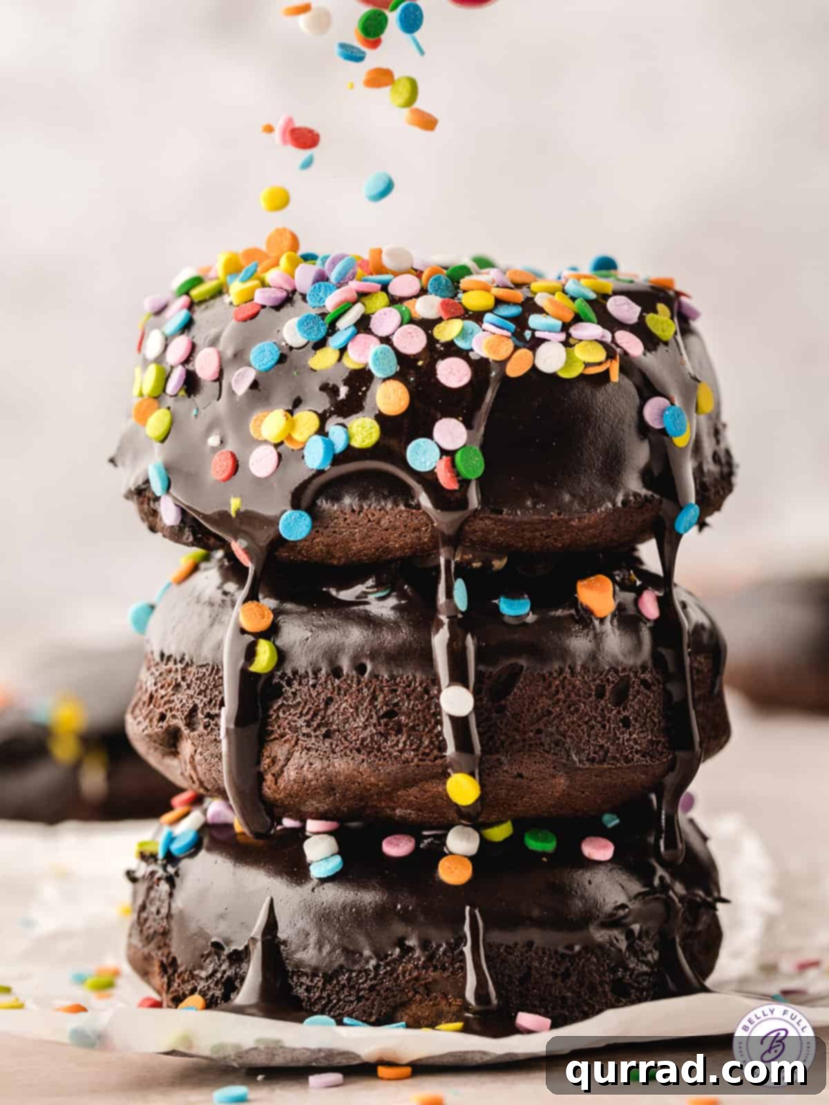 A stack of three perfectly glazed bronuts, adorned with colorful sprinkles