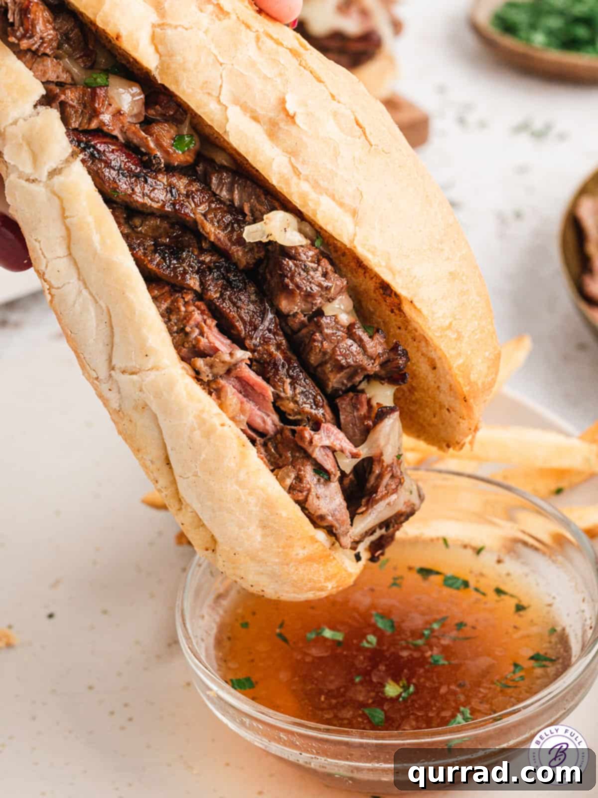 A delectable crockpot French dip sandwich being dipped into a small bowl of savory au jus, highlighting the rich broth.