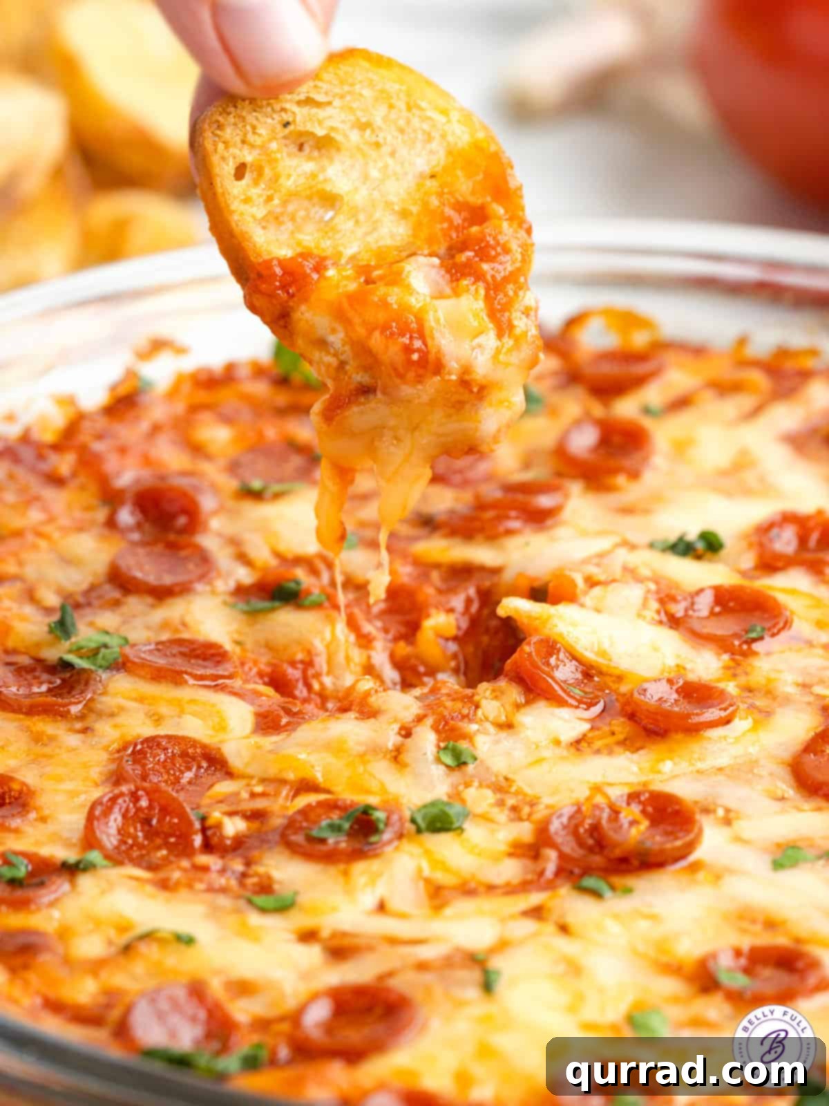 Made with just 5 ingredients (three of which are cheese!), this Pizza Dip is a party appetizer everyone will enjoy! Easy & cheesy! Crostini being dipped into a hot, bubbly pizza dip, showing the gooey cheese pull.