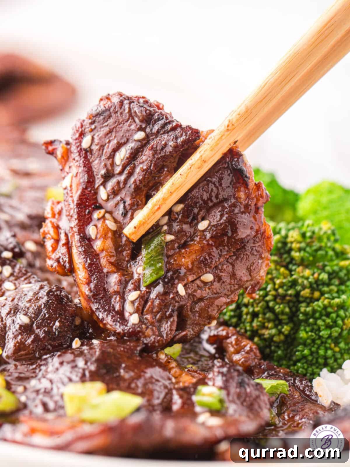 Delicious Korean Short Rib with Chopsticks Large piece of marinated Korean beef short rib held between chopsticks, ready to eat.