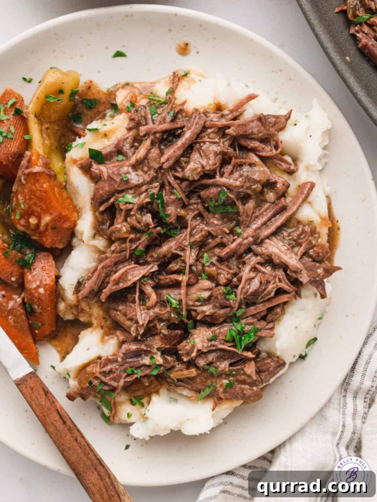 Southern Comfort Mississippi Pot Roast 7 A plate of tender Mississippi Pot Roast served alongside creamy mashed potatoes, garnished with fresh herbs.