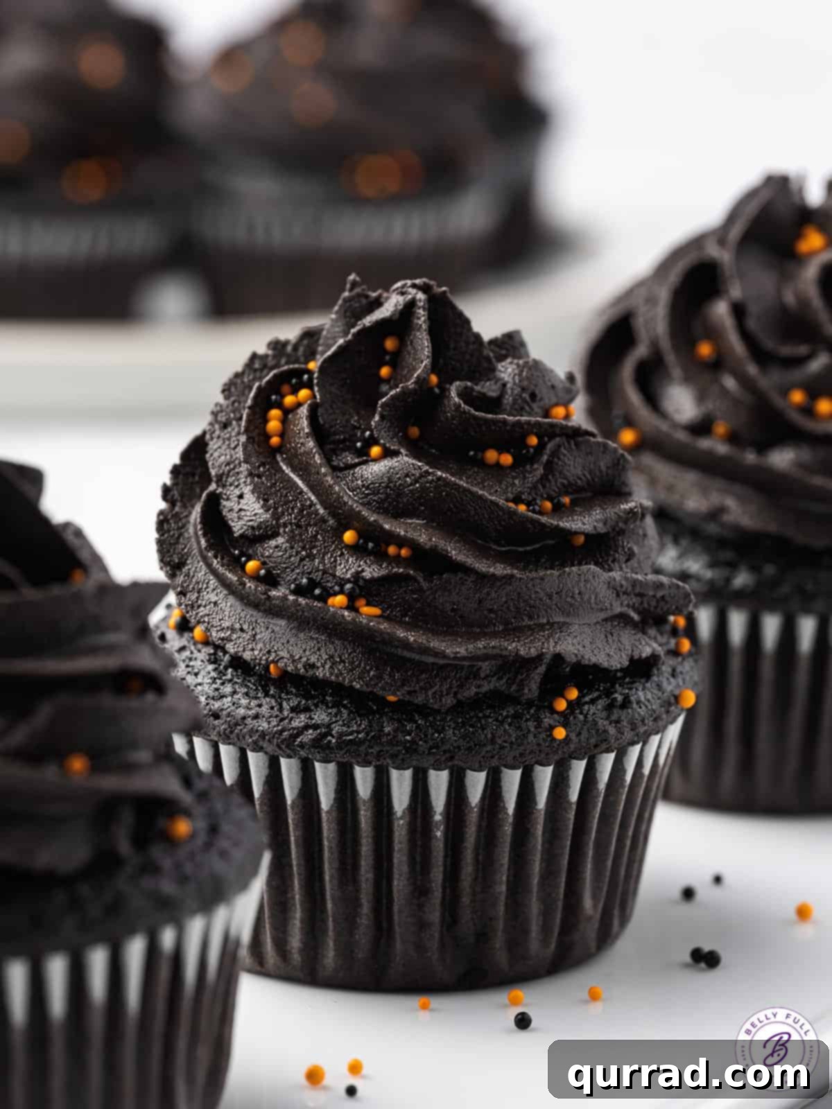 Three black cupcakes with black buttercream frosting
