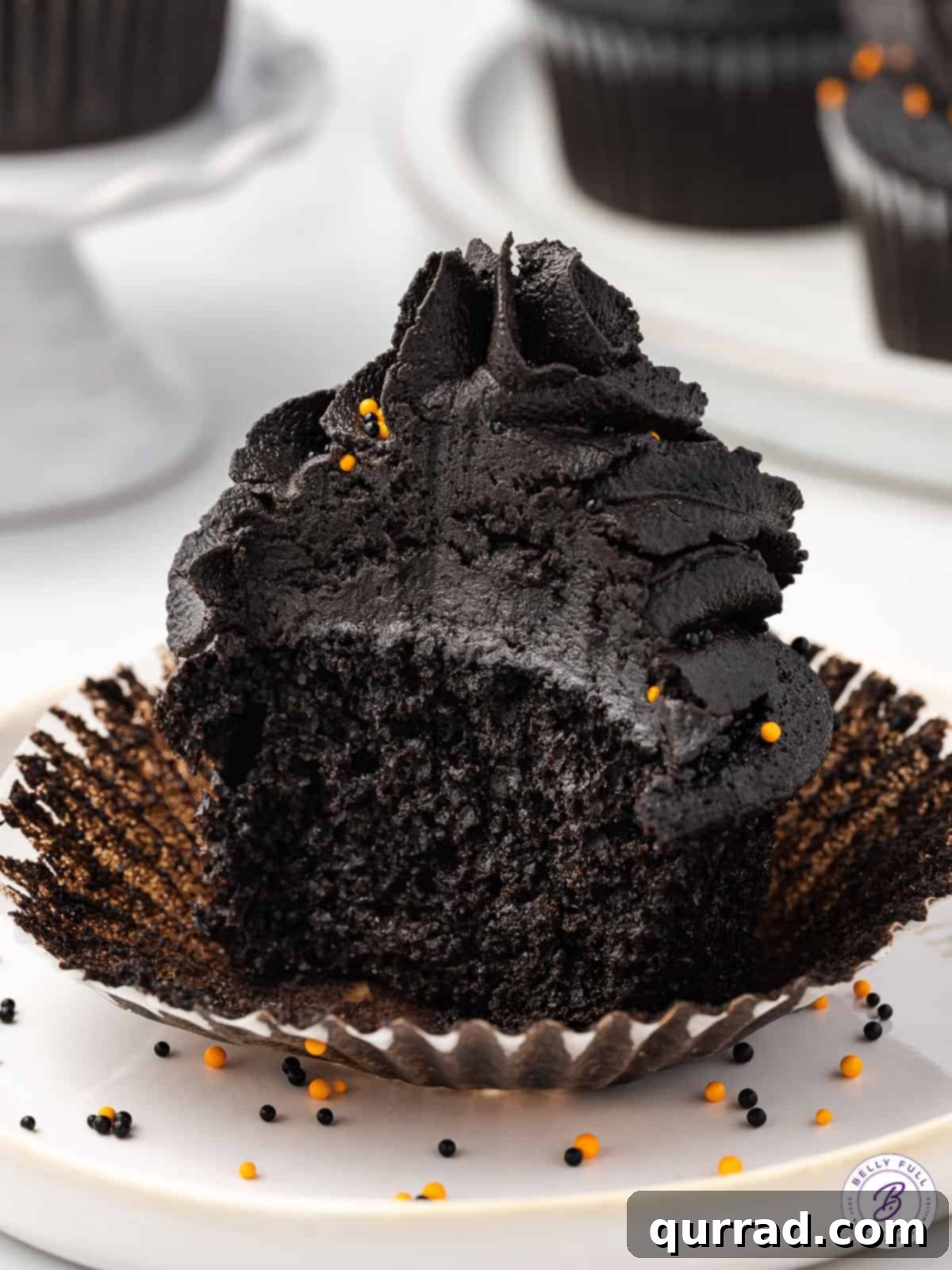 A black velvet cupcake with buttercream frosting cut in half