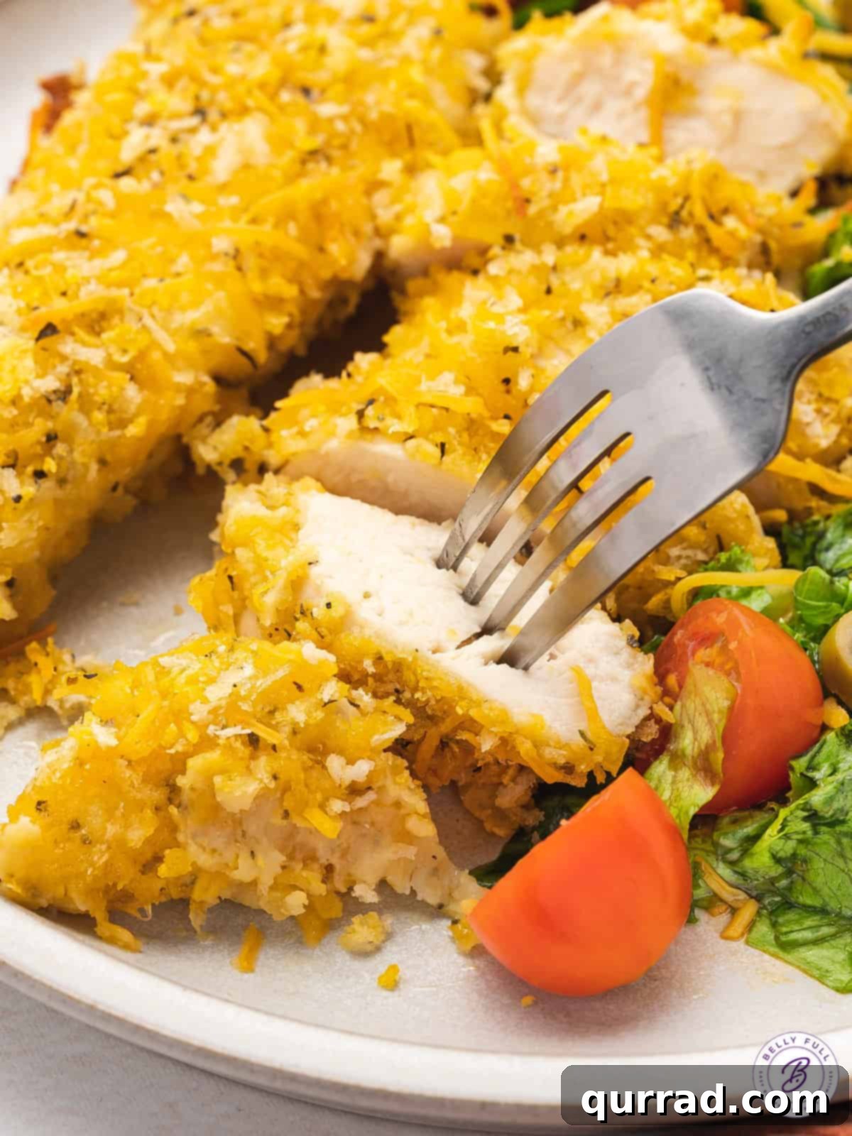 A fork piercing a piece of cheesy chicken, showing the tender inside and crispy crust