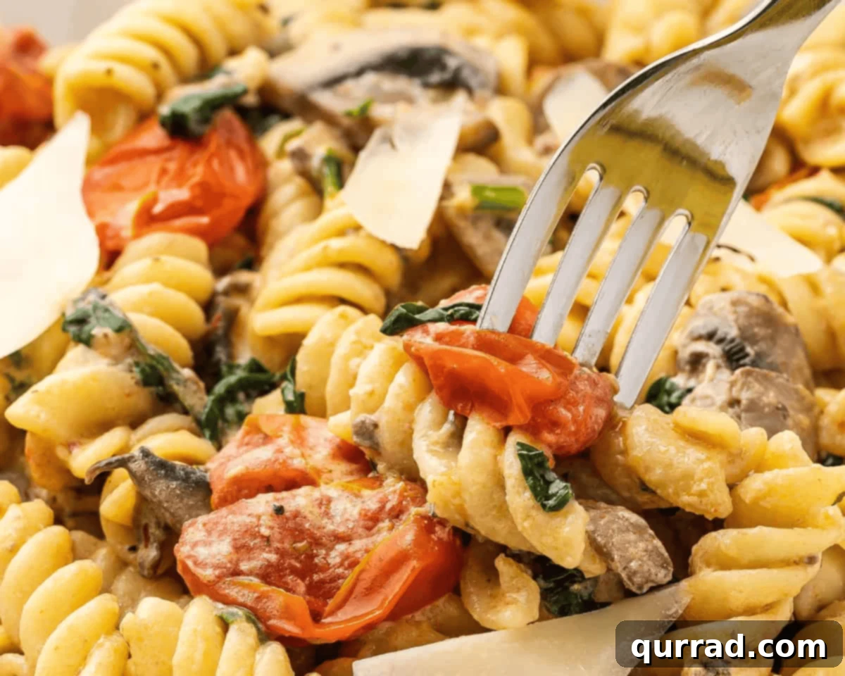 Based on the viral TikTok recipe, Baked Boursin Pasta is made with rotini, veggies, and garlic and herb Boursin cheese. Ready in 35 minutes! A fork taking a portion of Boursin cheese pasta topped with shaved Parmesan.