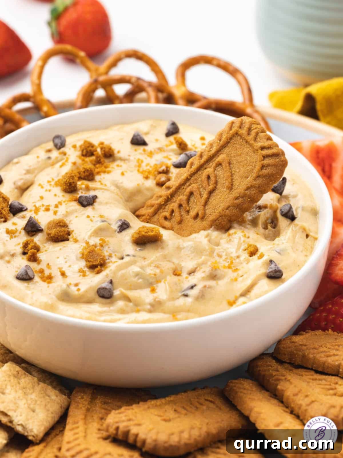 Every bite of this Biscoff Dip is infused with sweet cookie butter flavor! Made with cream cheese, marshmallow fluff, and cookie butter. A bowl of creamy Biscoff dip, garnished with a whole Biscoff cookie resting inside it, ready for dipping.