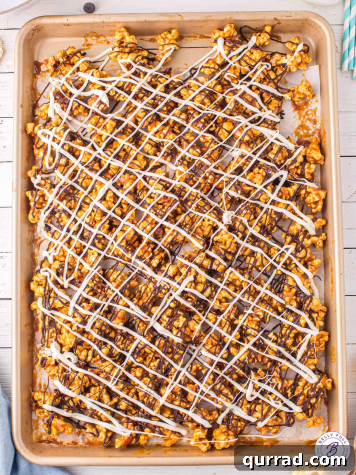 Duotone Chocolate Popcorn Treat 3 sheet pan of caramel corn with melted dark and white chocolate
