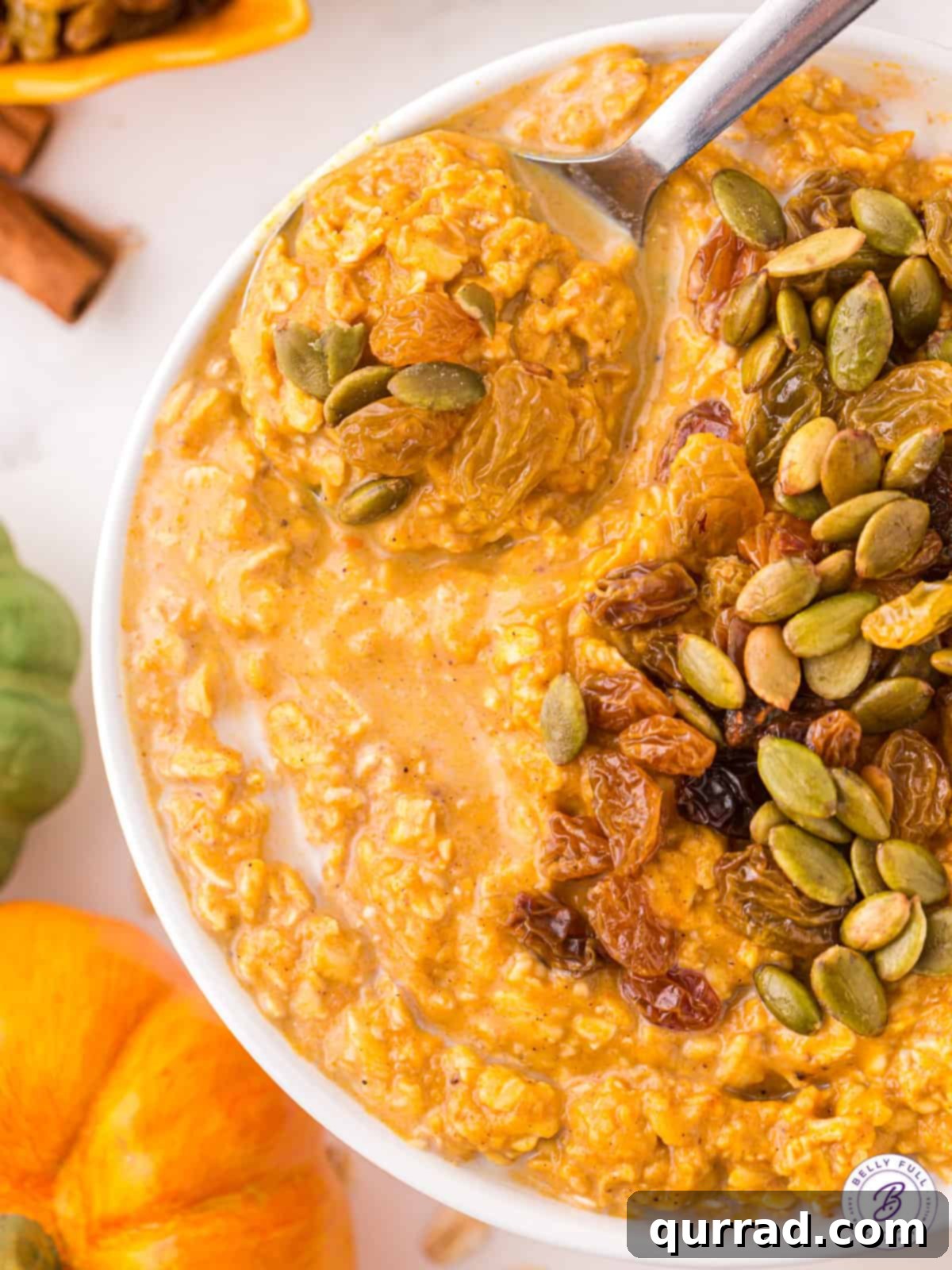 Pumpkin oatmeal is made with wholesome ingredients like oats and pumpkin puree and spiced with warm flavors of pumpkin pie spice, showing the finished dish. A close-up view of a bowl of pumpkin oatmeal, garnished with nuts and seeds, ready to be eaten.
