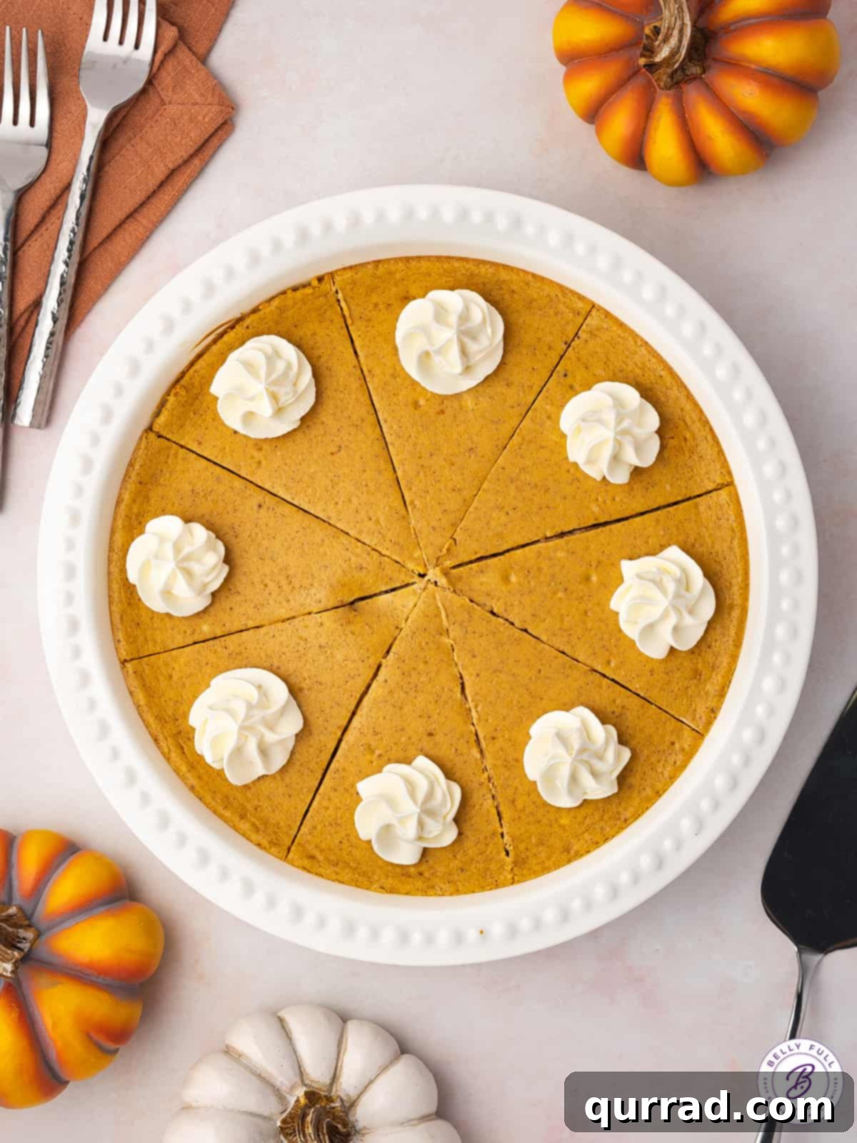 An overhead view of an entire layered pumpkin cheesecake, garnished lightly, ready to be sliced.