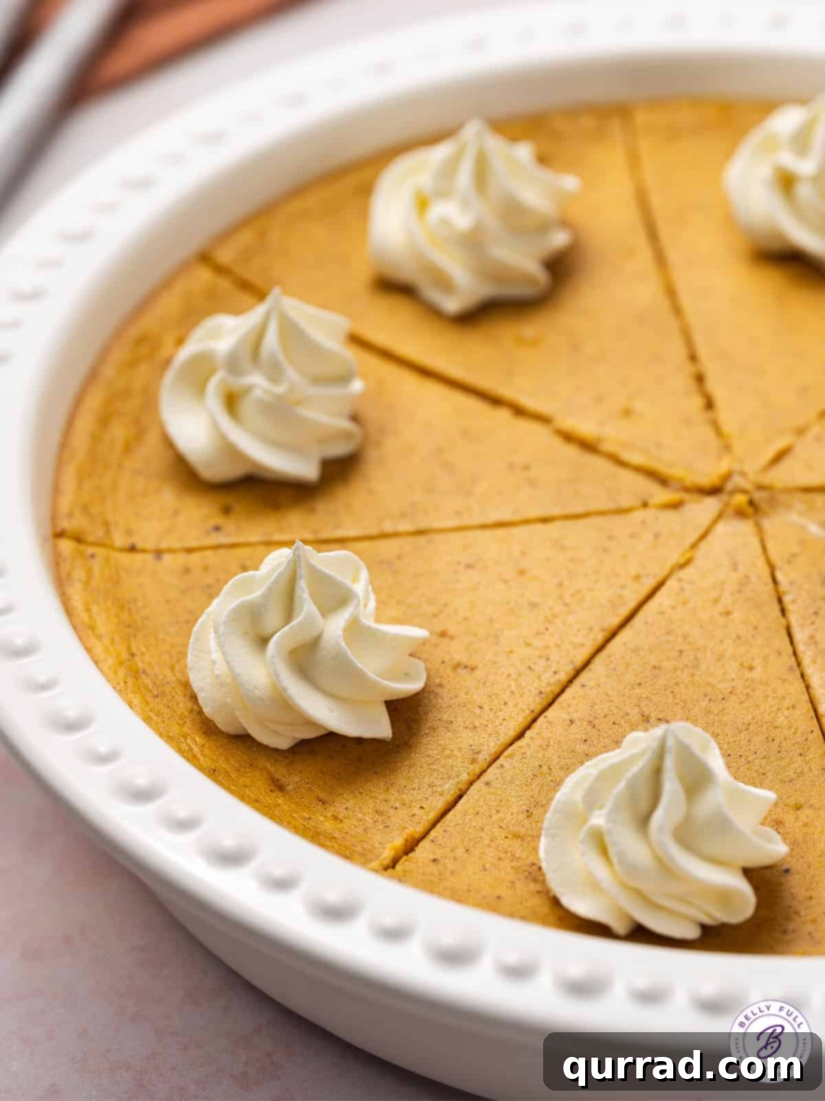 A close-up shot of a sliced pumpkin cheesecake, clearly showing the distinct layers of crust, plain cheesecake, and spiced pumpkin cheesecake.