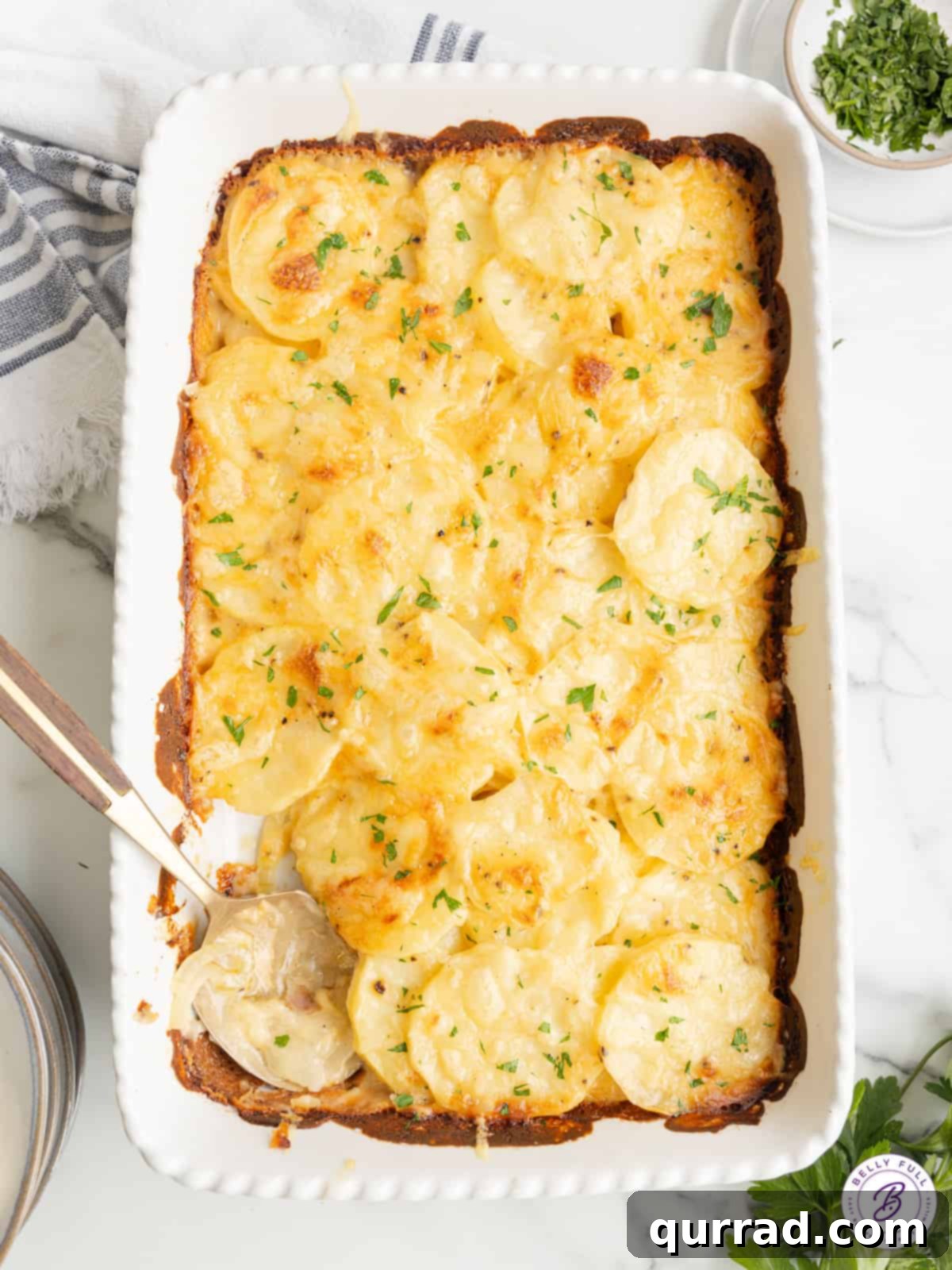 The Ultimate Creamy and Cheesy Au Gratin Potatoes for Any Meal An overhead shot of a freshly baked casserole dish of au gratin potatoes, golden brown and bubbling with melted cheese and a sprinkle of fresh herbs.