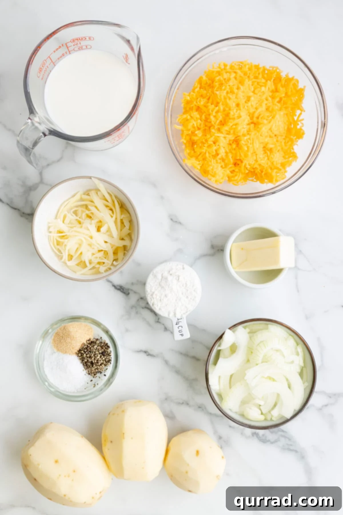 Au Gratin Potatoes 3 All ingredients laid out on a wooden board, including peeled russet potatoes, a small onion, butter, flour, milk, cheddar cheese, Gruyère cheese, and seasonings.