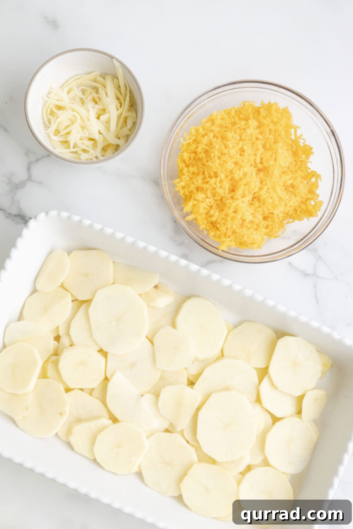 Au Gratin Potatoes 5 Layers of thinly sliced potatoes and onions arranged neatly in a white ceramic casserole dish, ready for the cheese sauce.