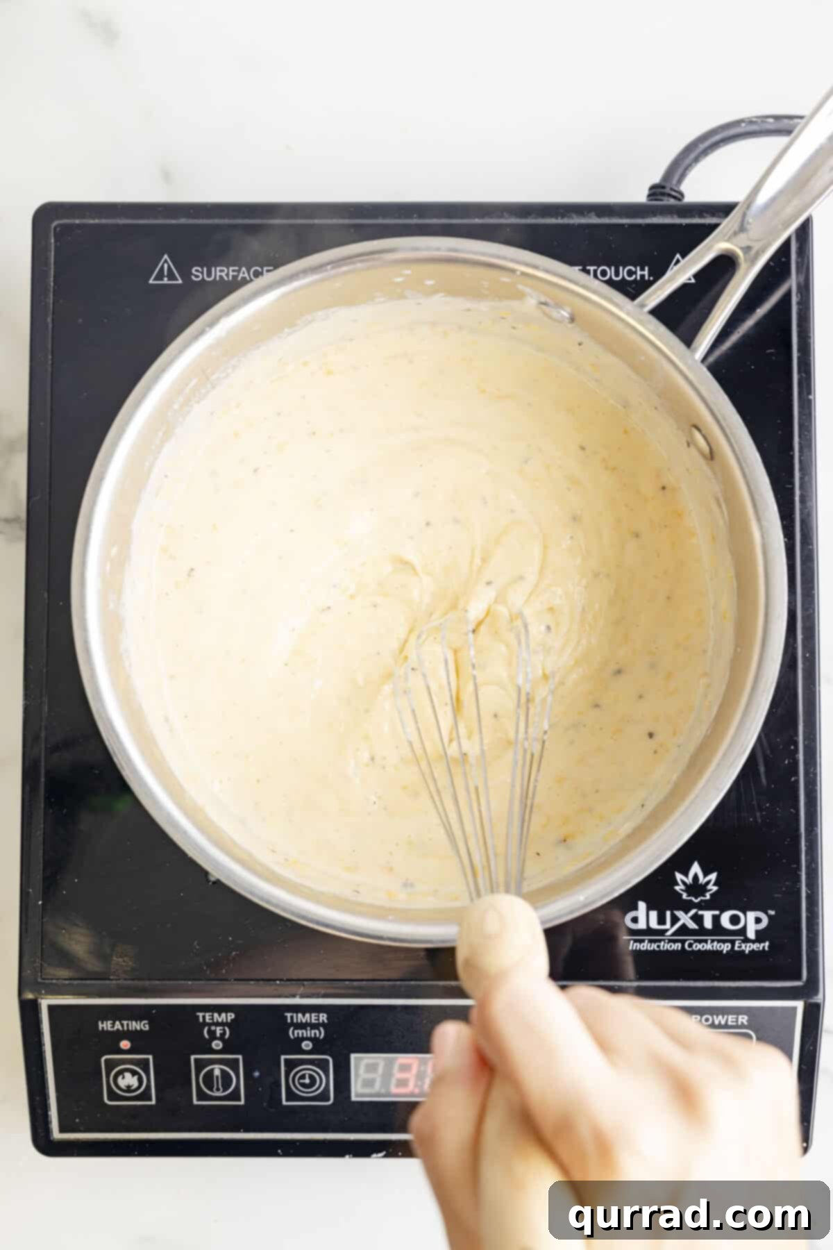 Au Gratin Potatoes 6 A creamy, golden cheese sauce being prepared in a saucepan on the stovetop, with butter, flour, milk, and shredded cheese melting together.