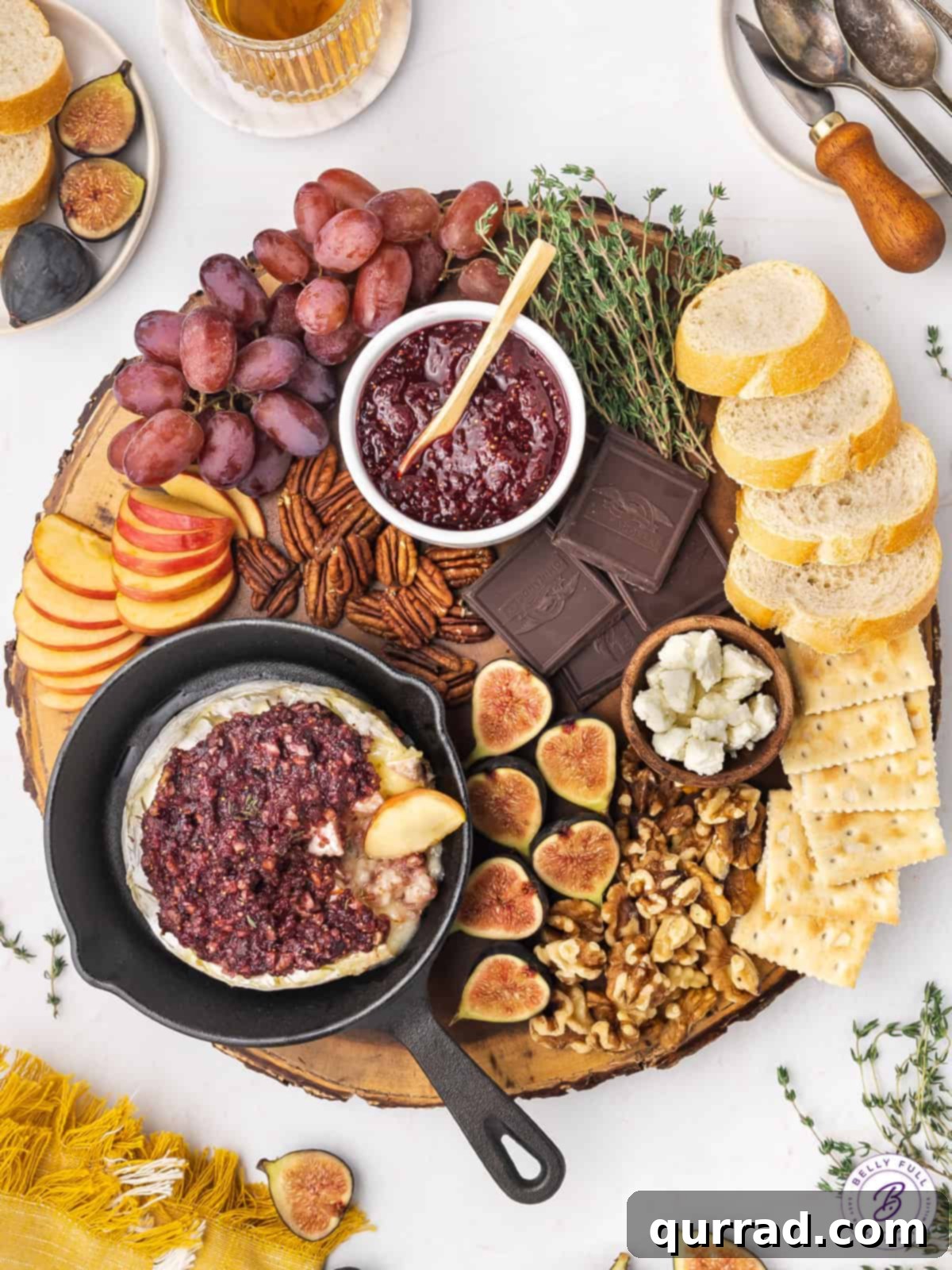 Overhead view of a platter with a skillet of baked brie, bread, crackers, and fruit