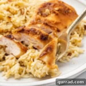A bite of chicken on a fork with a serving of No-Peek Chicken and Rice Casserole
