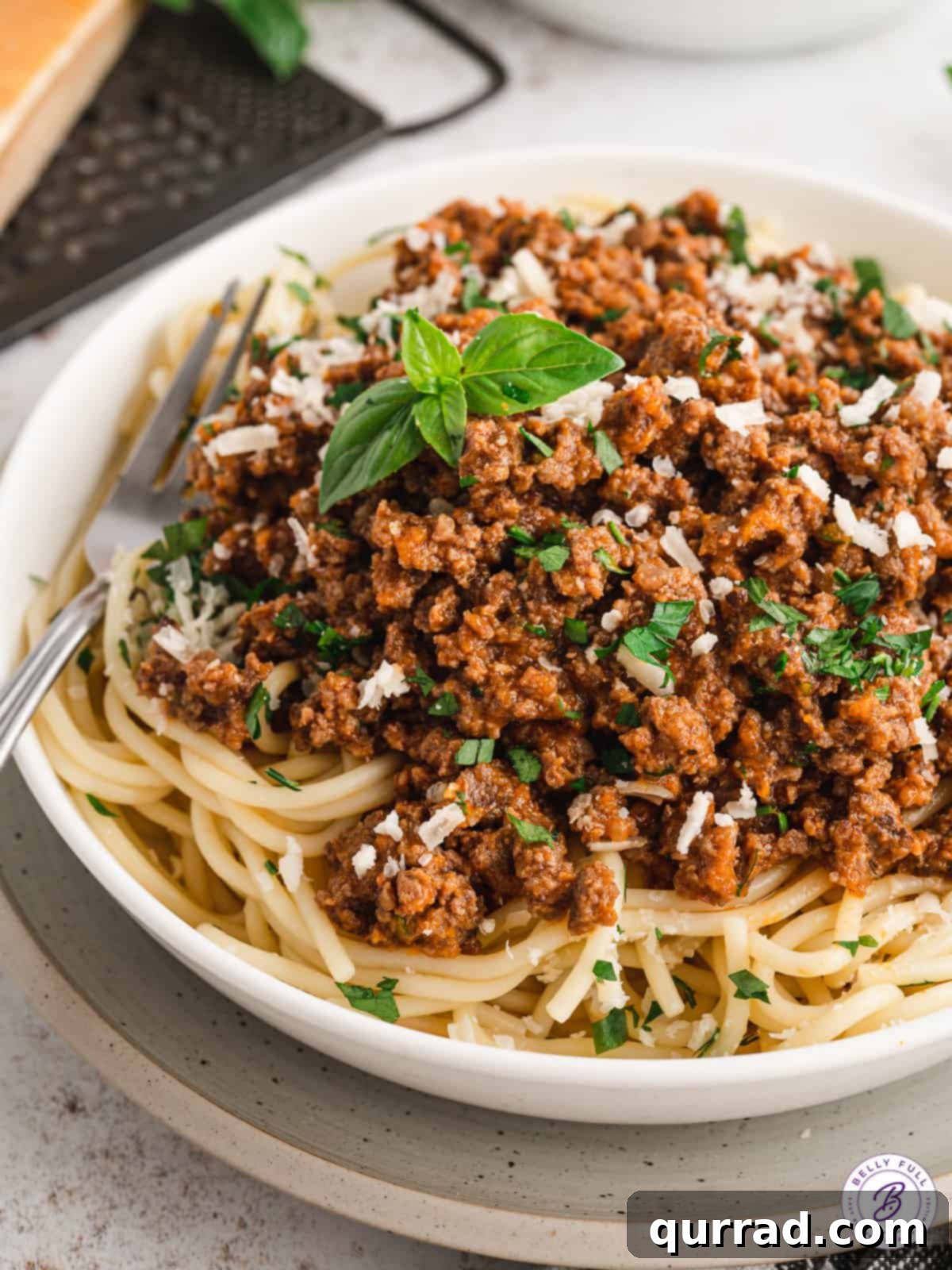 Indulge in a classic: spaghetti perfectly coated with our delightful Magic Meat Sauce. Overhead view of perfectly cooked spaghetti generously topped with Magic Meat Sauce and fresh herbs.