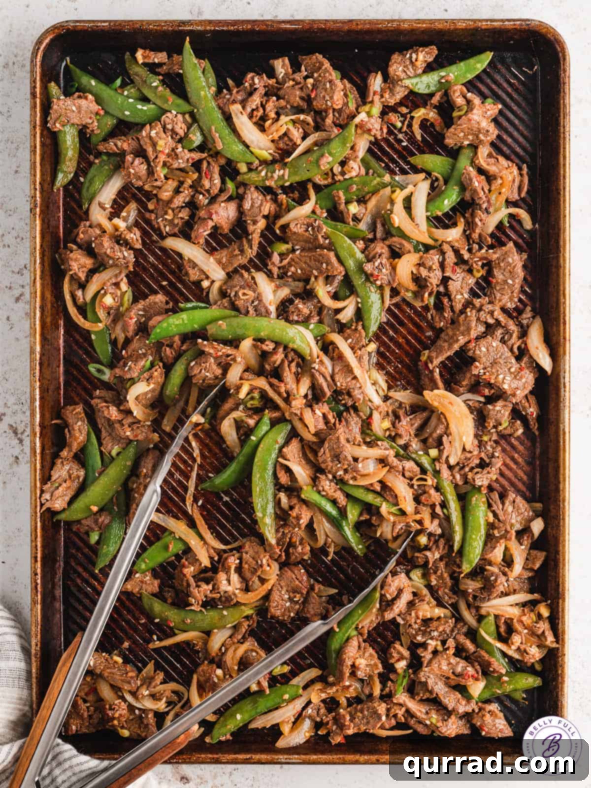 One-Pan Korean BBQ Beef 5 Tongs on a sheet pan of beef bulgogi and roasted vegetables