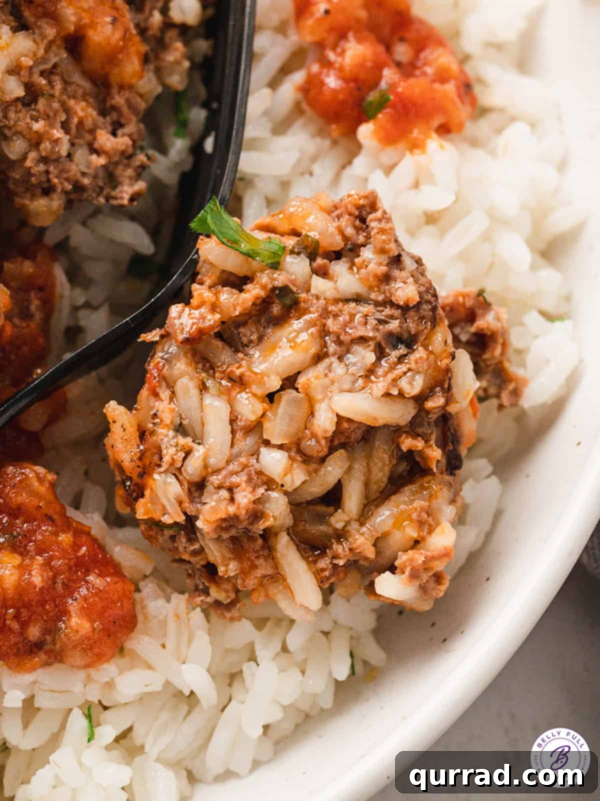 Close up of a porcupine meatball on a bed of rice, showing the cooked rice grains