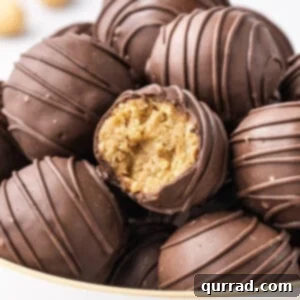 A bowl of chocolate covered peanut butter balls with one cut open to show the inside