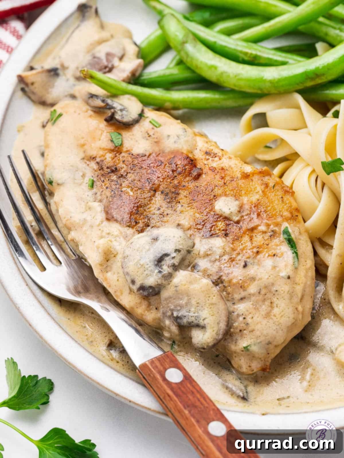 Boursin Chicken is a simple weeknight dinner made with juicy chicken breasts in a mushroom and garlic herb Boursin cheese white wine sauce. Boursin cheese chicken on a plate with pasta and green beans, garnished with parsley.