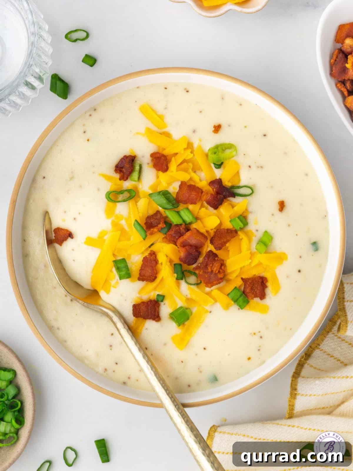 Copycat Panera Baked Potato Soup is rich, creamy, and full of incredible flavor, thanks to ingredients like cream cheese and bacon. Overhead view of a bowl of baked potato soup with shredded cheese and bacon, inviting and delicious.