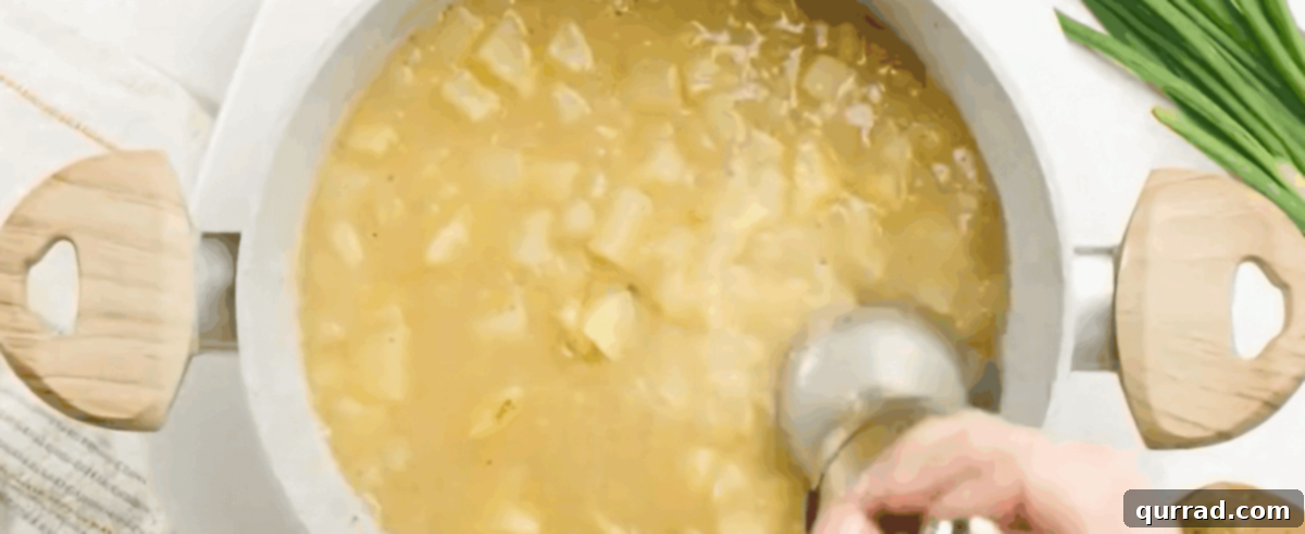 Creamy Roasted Potato Soup 6 Using a handheld immersion blender to achieve the desired creamy consistency for the potato soup directly in the pot.