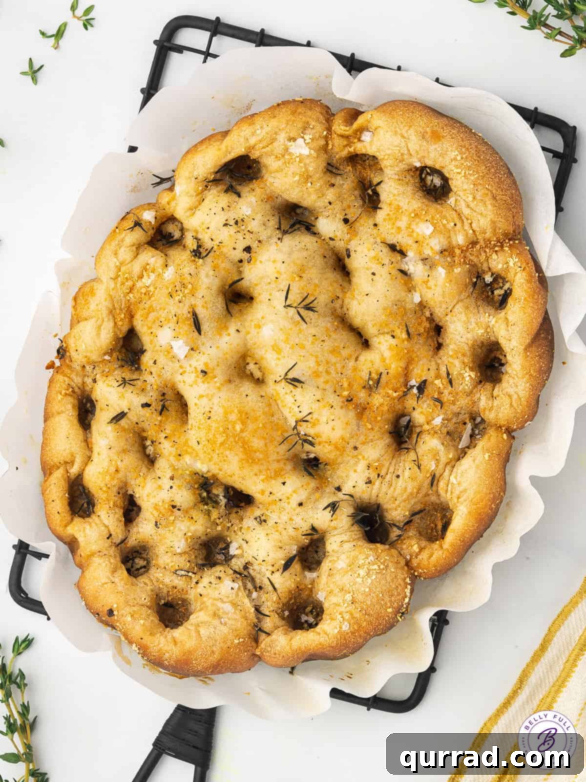Golden brown crockpot focaccia presented on a serving platter, sprinkled with herbs and parmesan, inviting a delicious tasting experience.