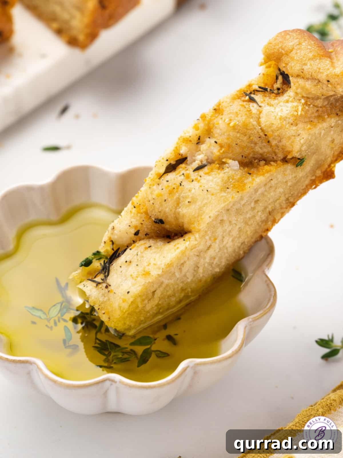 A slice of slow cooker focaccia being dipped into a bowl of rich olive oil, highlighting its soft texture and golden crust.