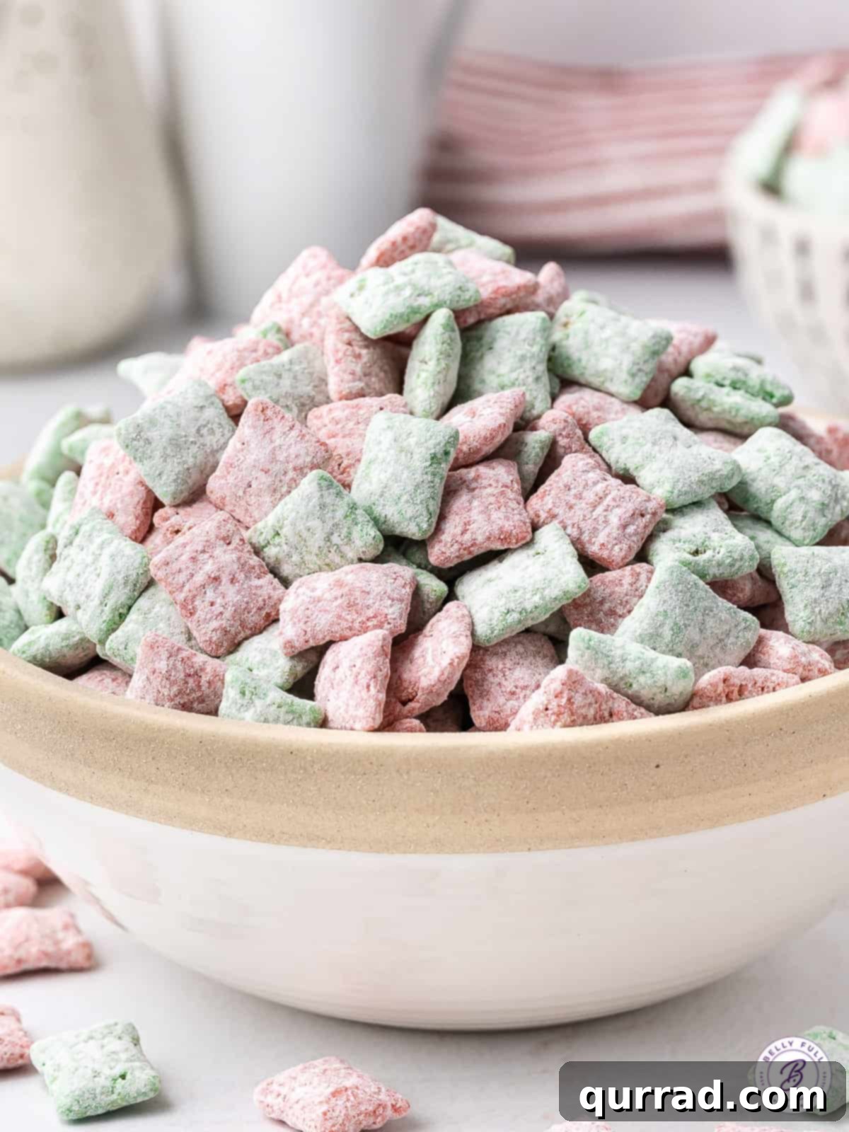 Santa's Sweet Snow Bites 2 Christmas Muddy Buddies piled high in bowl, showcasing festive red and green colors