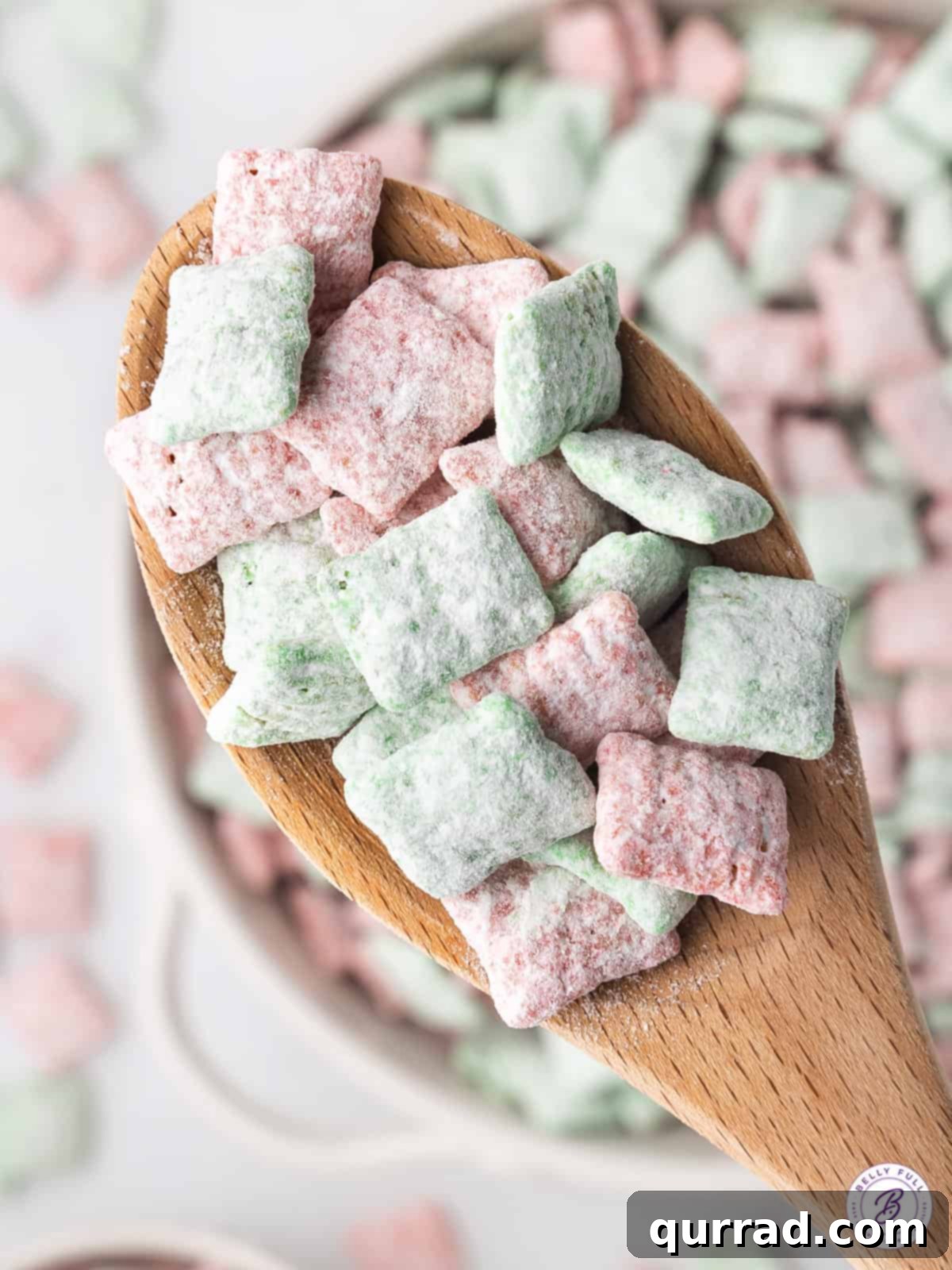 Santa's Sweet Snow Bites 5 Scoop of red and green muddy buddies on a wooden spoon, ready to be enjoyed