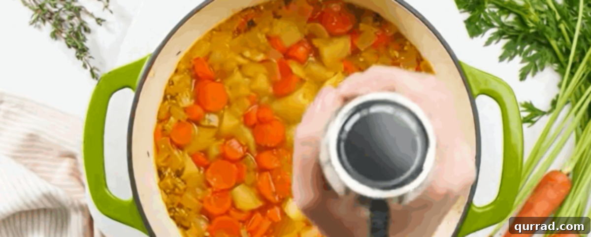 Using an immersion blender to blend the soup until smooth.