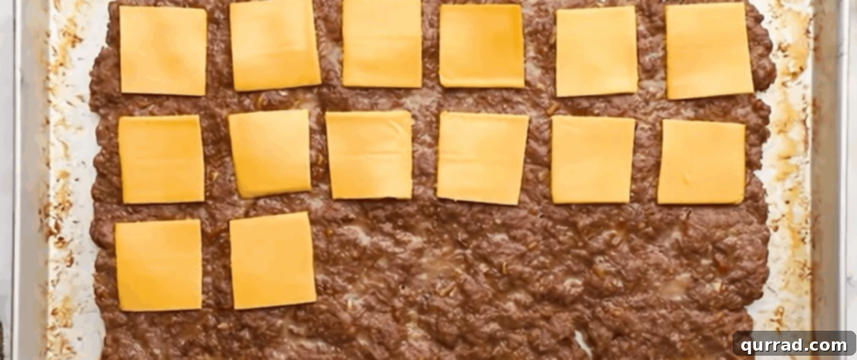 White Castle: The Original American Slider 5 Melted American cheese slices laid precisely over the scored, cooked meat slab on the baking sheet, ready to go back into the oven.