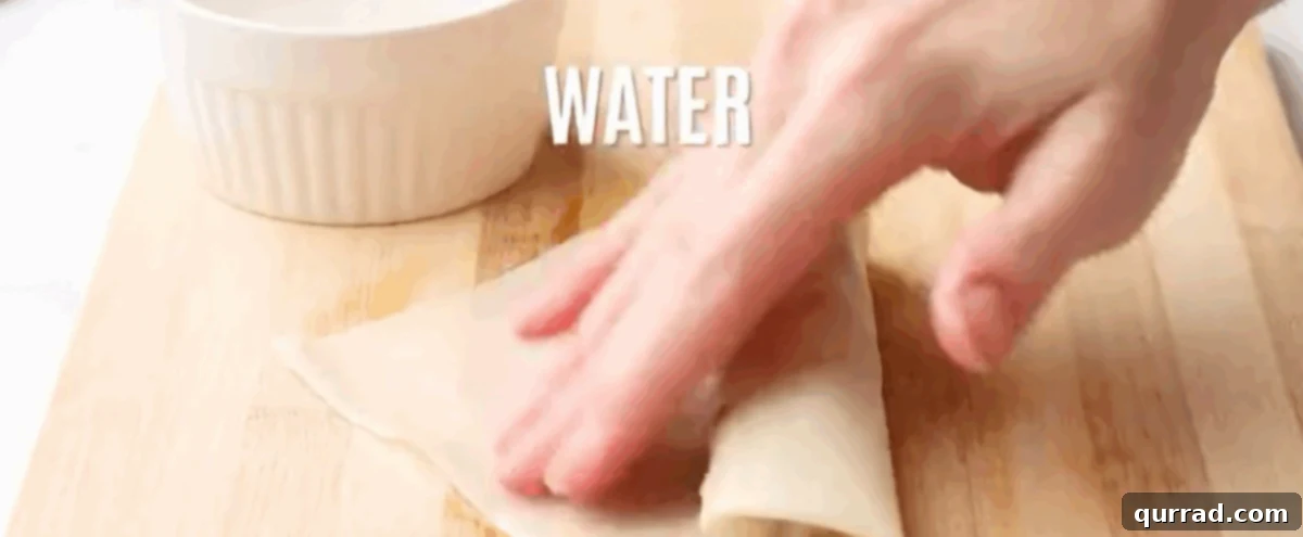 Crispy Filipino Delights 6 Sealing the rolled lumpia wrapper with a touch of water.