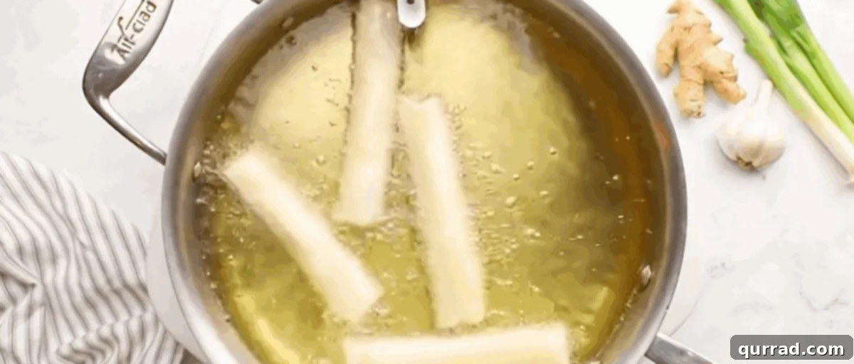 Crispy Filipino Delights 7 Four lumpia deep frying in a pot until golden brown.