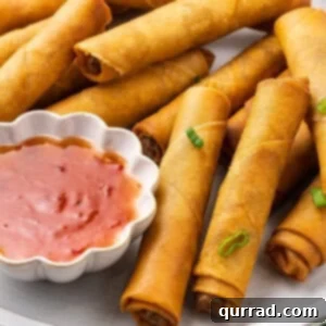 A plate of pork lumpia with a dish of sweet chili sauce