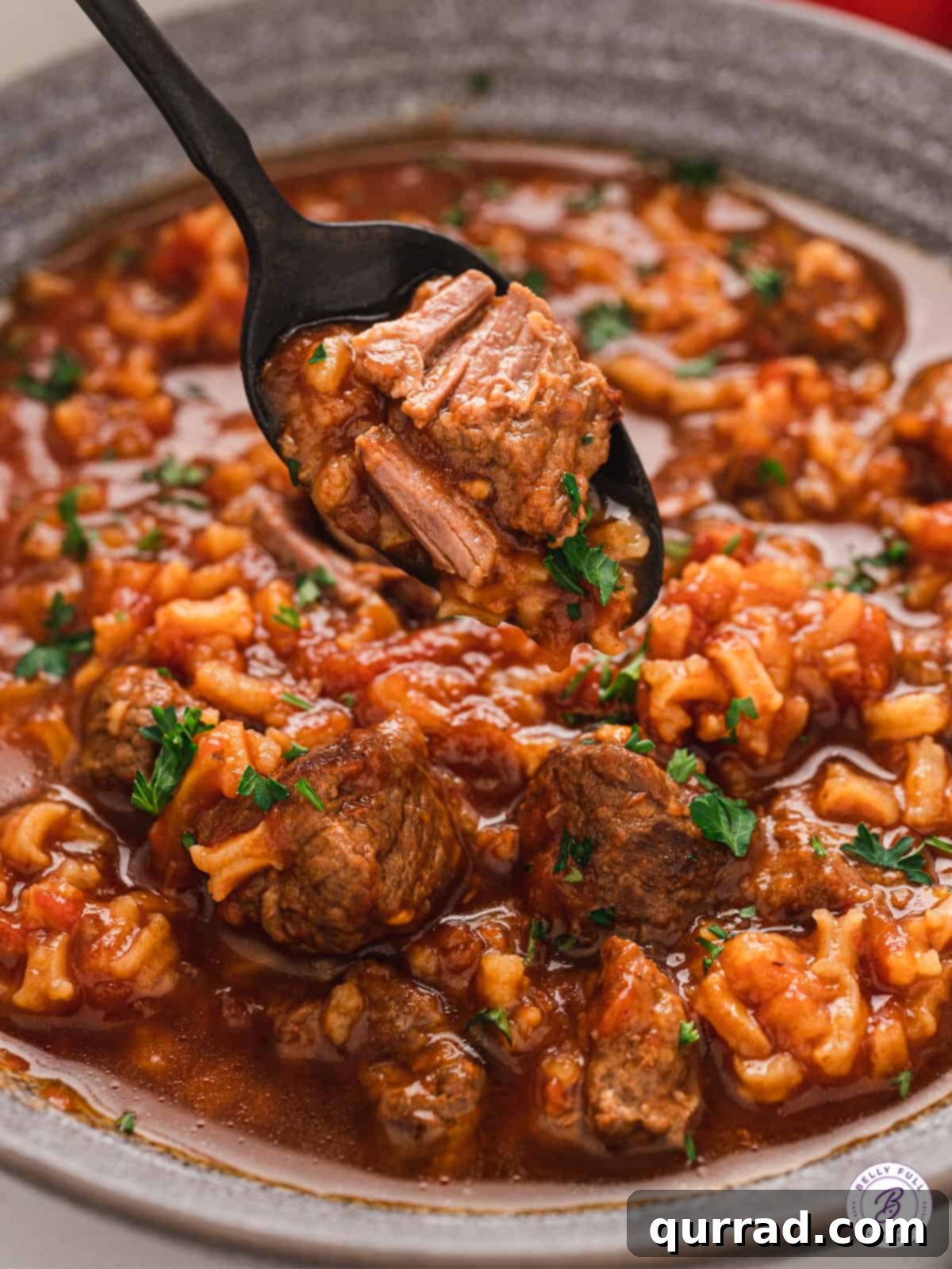 A spoon in a bowl of ready-to-eat tomato rice soup, showing the rich texture.