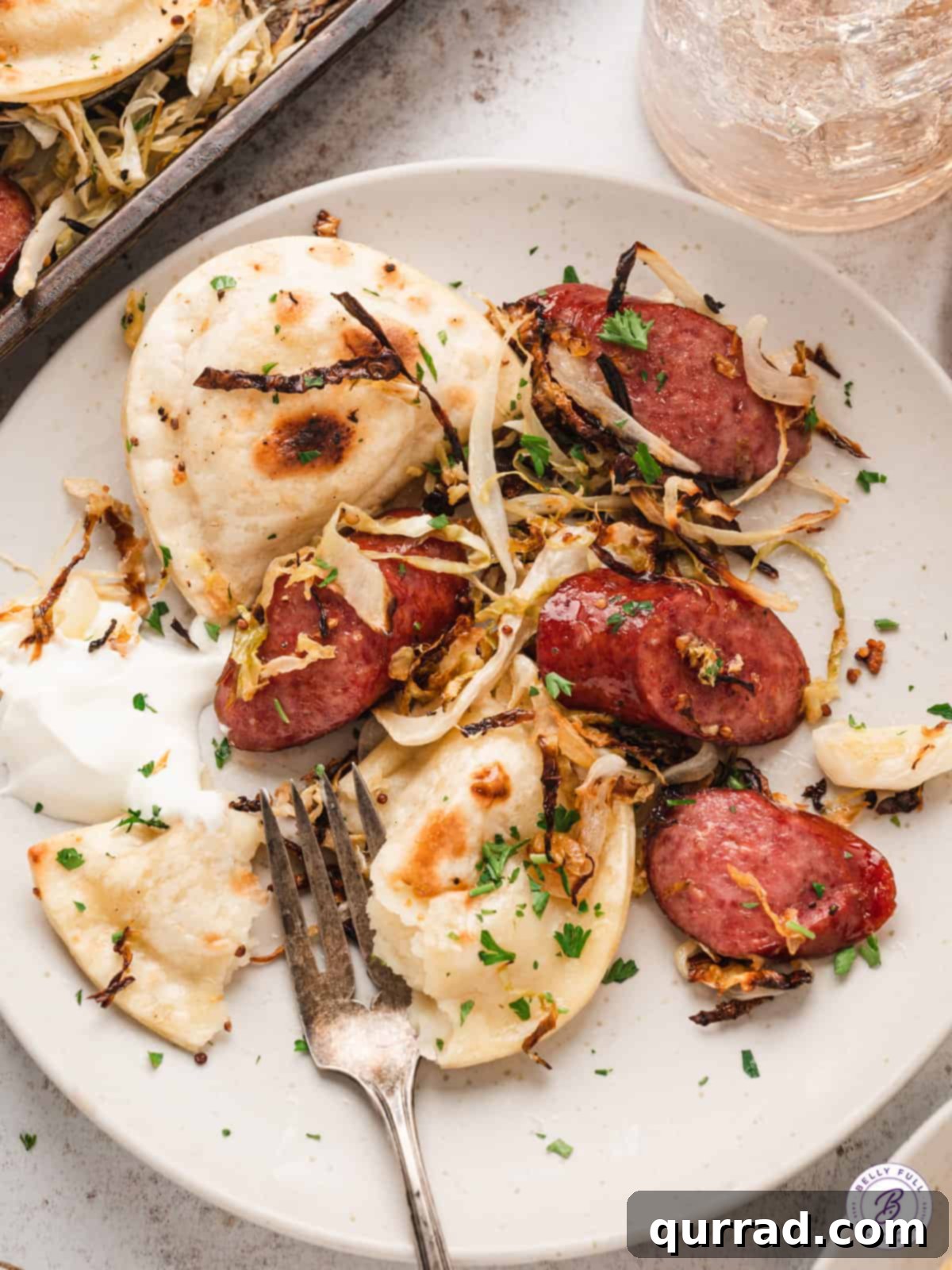 A serving of Sheet Pan Pierogi and Sausage on a plate, garnished with fresh parsley, ready to eat.