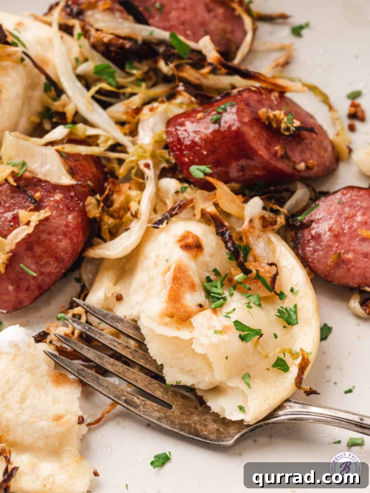 Close-up of a plated serving of Sheet Pan Pierogi and Sausage with sour cream and mustard for dipping.