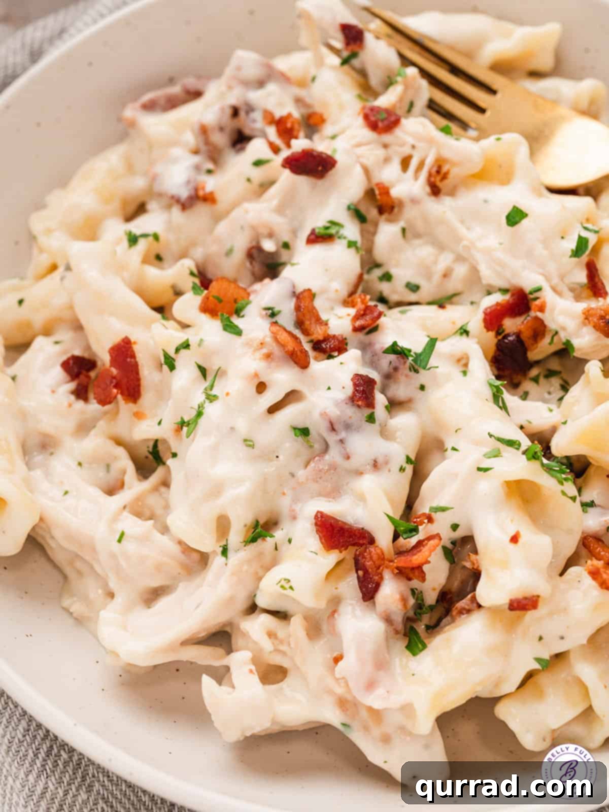 This Chicken Bacon Ranch Pasta is creamy and cheesy with pieces of shredded rotisserie chicken and salty thick-cut bacon. Close up of chicken bacon ranch pasta with a fork.
