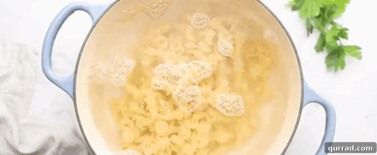 Loaded Chicken Bacon Ranch Pasta 3 Boiling pasta in a pot with blue handles.