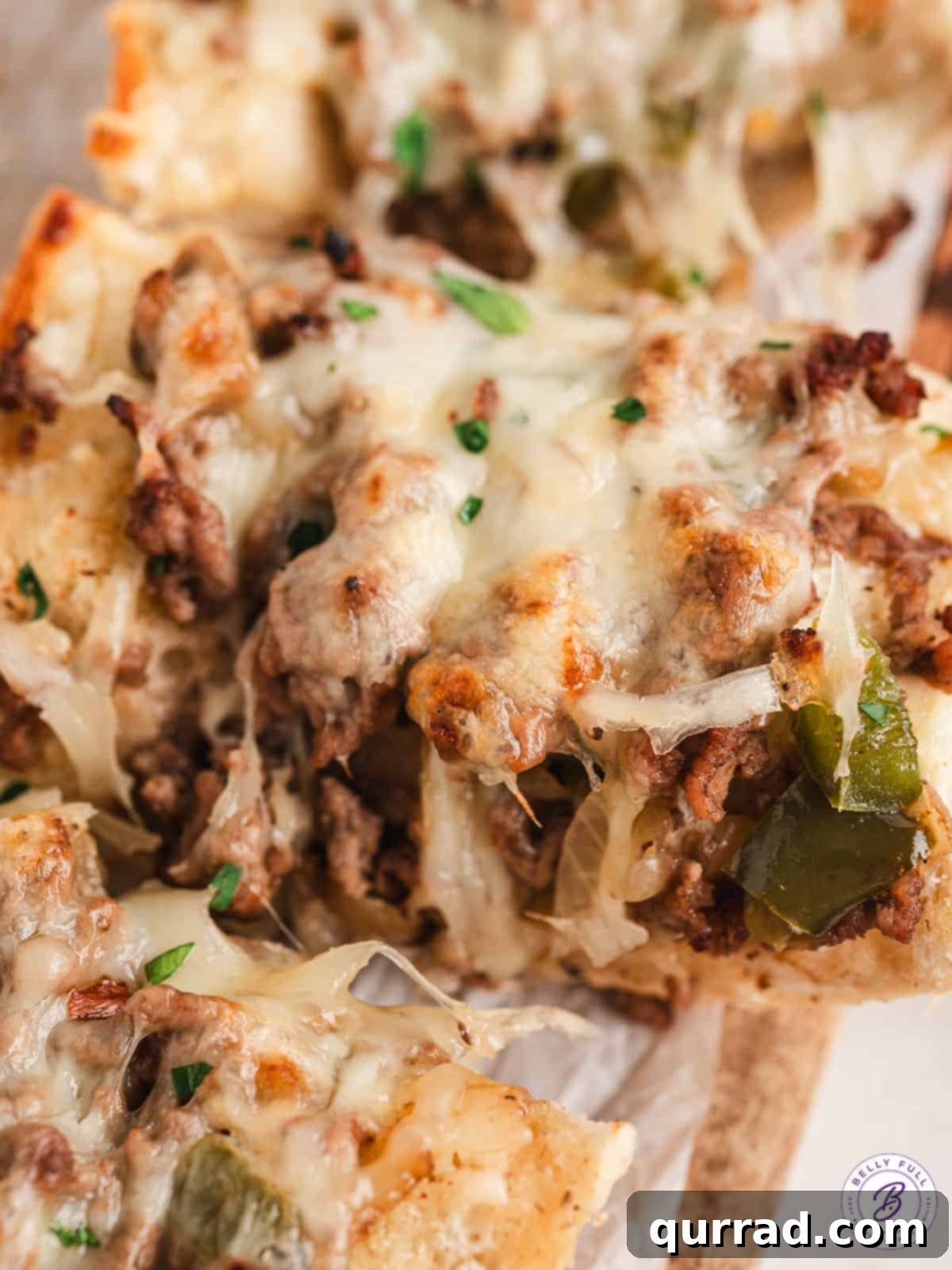 Close-up of perfectly baked slices of Philly cheesesteak cheesy bread, showcasing the melted cheese and hearty filling