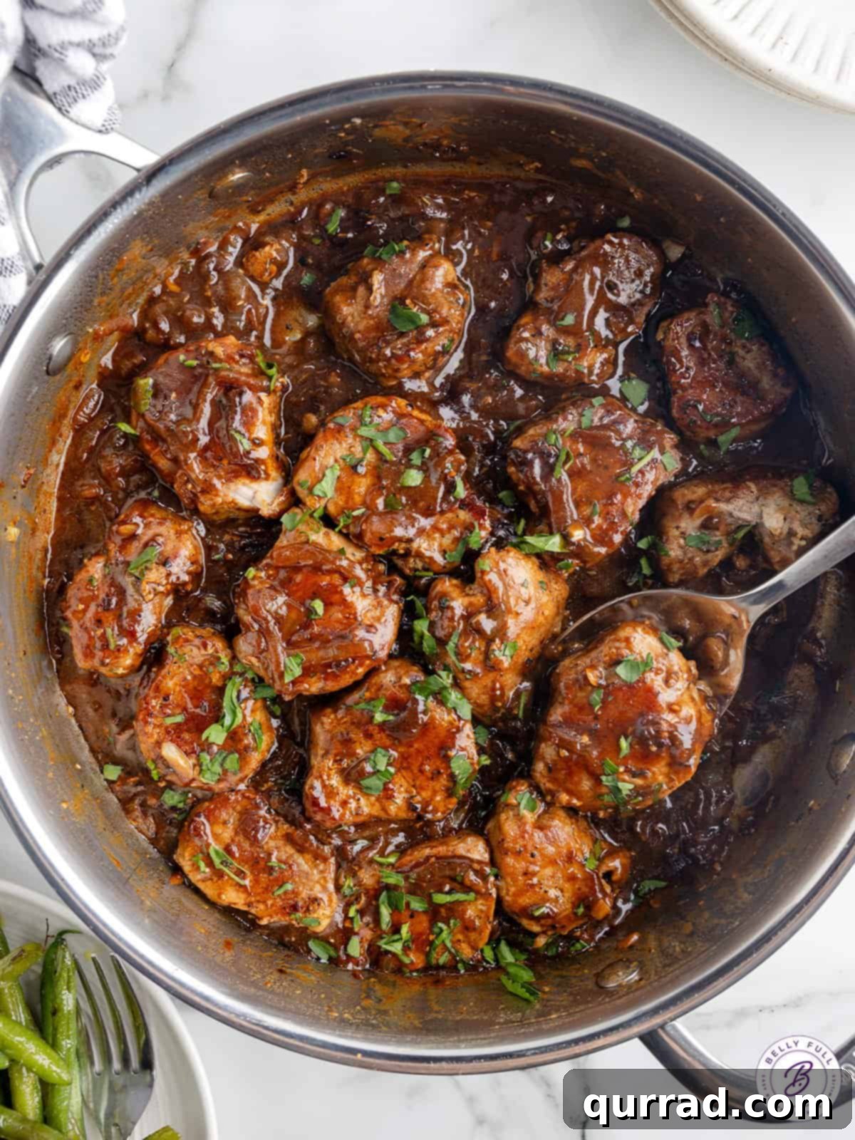 Pork Medallions with Onion Gravy in a Skillet Overhead view of a skillet showcasing golden-brown pork medallions immersed in a rich, dark brown caramelized onion gravy.