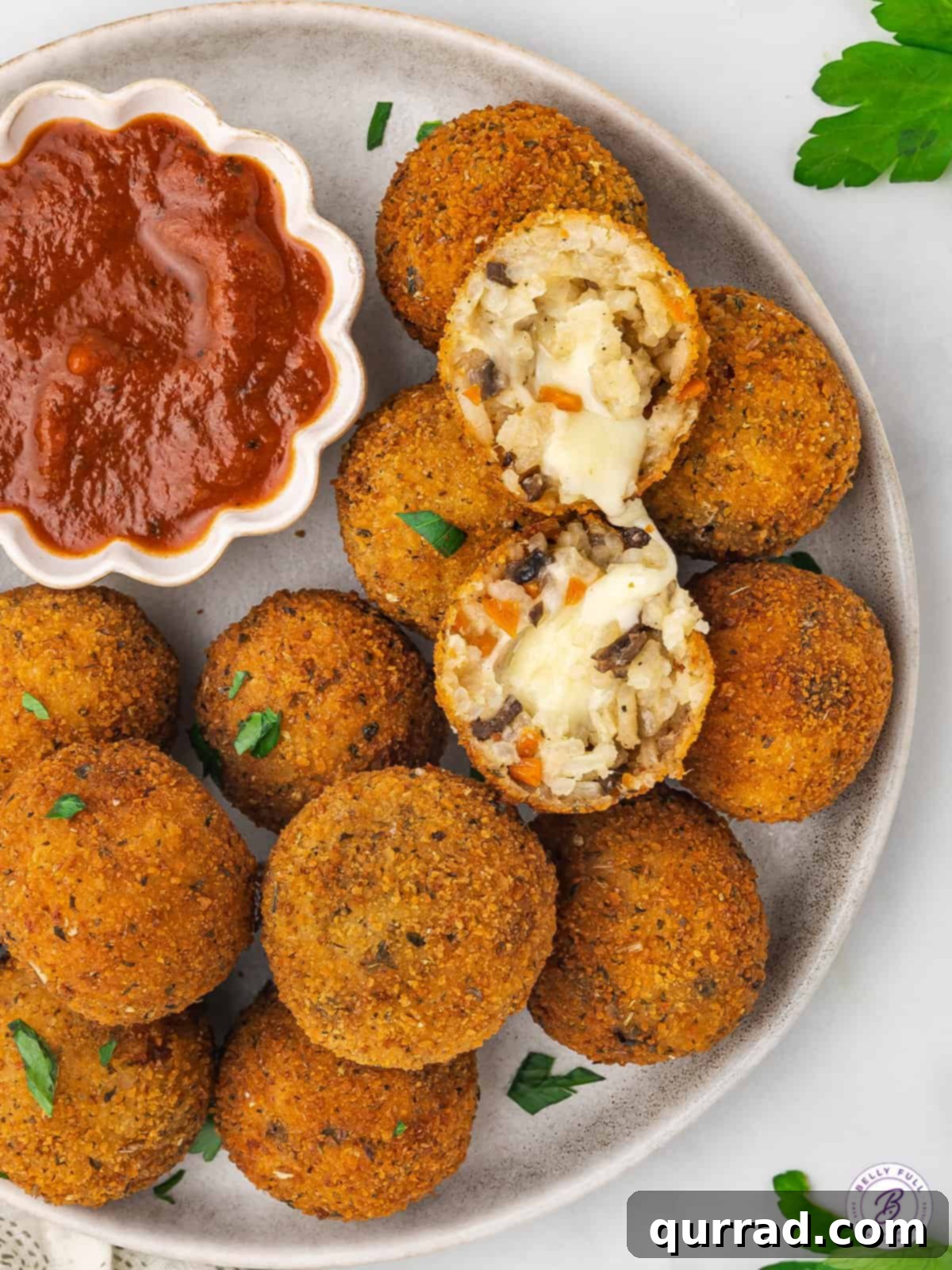 Creamy, Cheesy Risotto Arancini: The BEST Fried Italian Rice Balls A beautifully arranged plate of golden-fried arancini, with one rice ball cut open to reveal a luscious, melted cheese interior and creamy risotto.