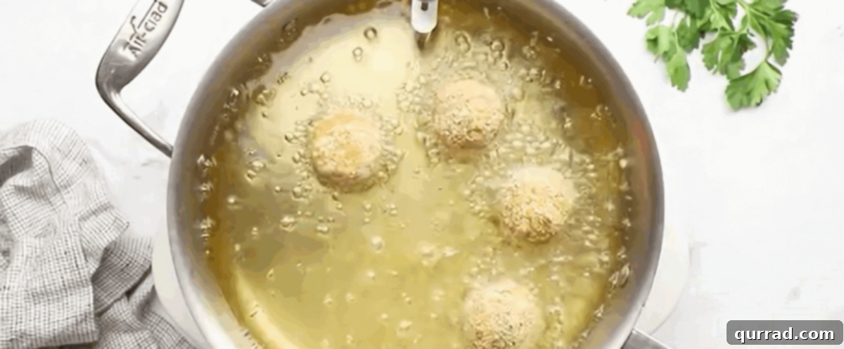 Crispy Golden Arancini 8 Golden-brown arancini frying in a pot of hot vegetable oil, showing their transformation into crispy Italian rice balls.