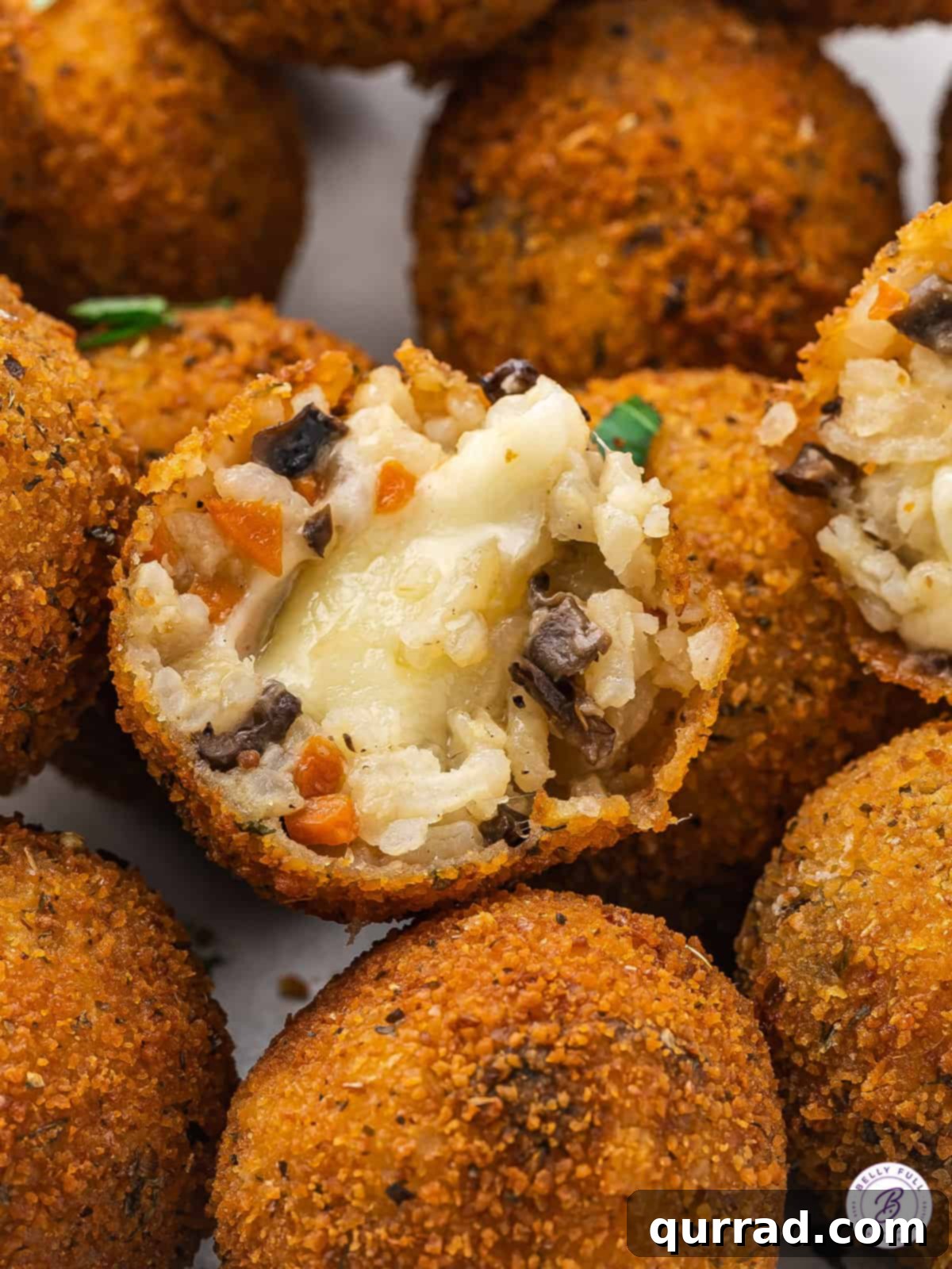 Inside the Perfect Arancini: Creamy Risotto and Melted Cheese Close-up of a single fried Italian rice ball, cut in half, revealing the perfectly melted Gruyère cheese and creamy risotto inside.